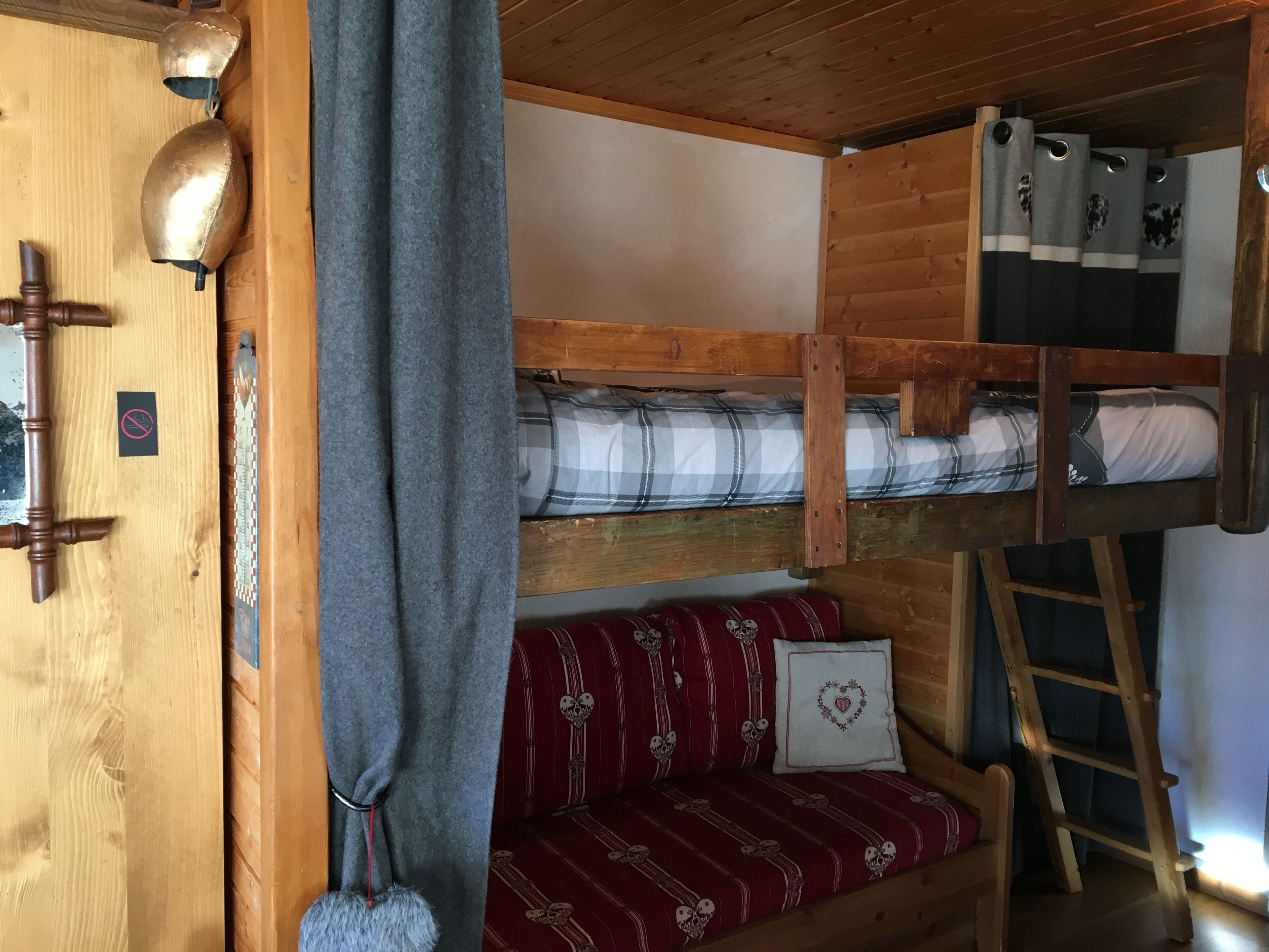 Een slaapkamer met stapelbed, houten deur, handdoekhouder, trapje en gordijn.
