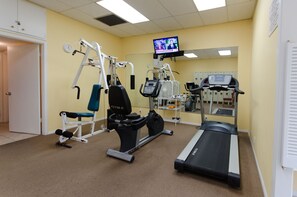 Un centre de remise en forme équipé de machines de cardio, d’appareils de musculation et d’un écran de télévision diffusant un programme d’information.