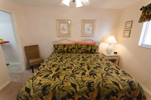 Une chambre à coucher avec un grand lit, une chaise, une table de chevet avec une lampe et des tableaux encadrés accrochés au mur.