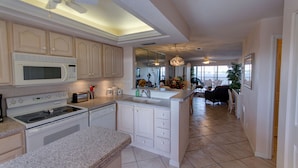 A spacious kitchen with white cabinetry, a microwave, stove, and a large island with a sink. - Million Dollar View  Bay Sunrises & Gulf Sunsets-Feb and March open 2025 (Sarasota)