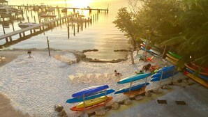 Una playa con un muelle, barcos y una hilera de canoas.