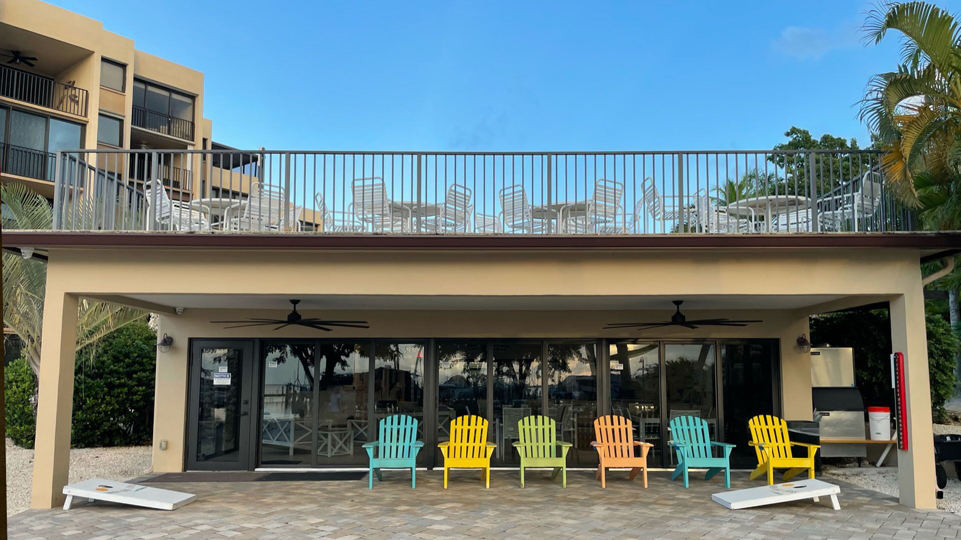 A covered outdoor seating area with colorful Adirondack chairs and a ceiling fan.