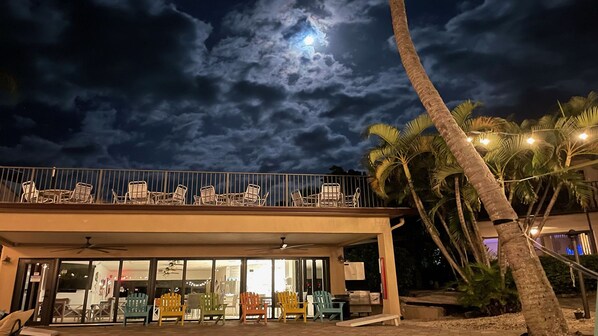 A building with a balcony overlooking palm trees and a cloudy sky.