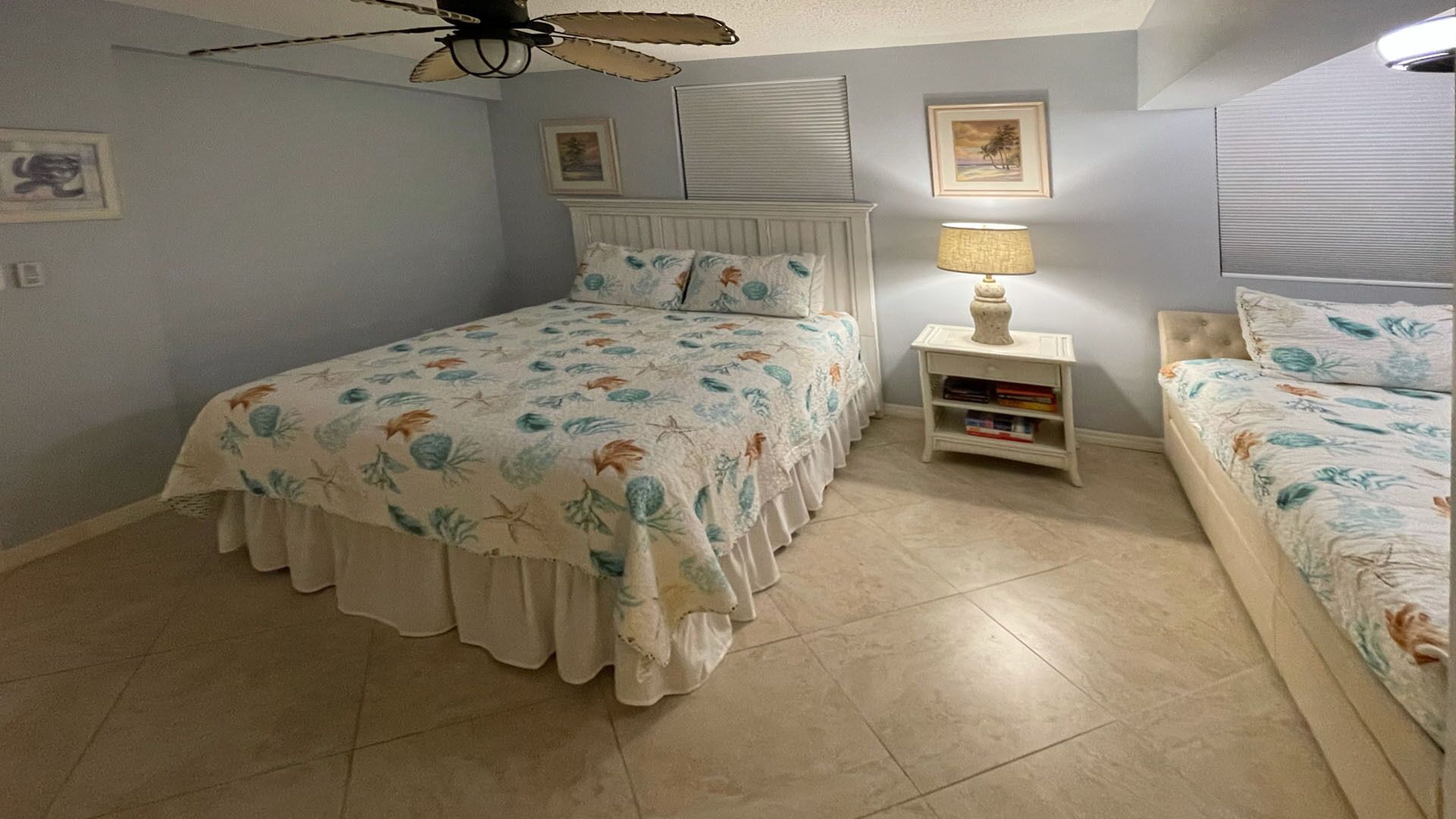 Un dormitorio con cama, mesita de noche, lámpara y ventilador de techo.