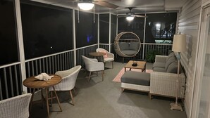 Ein überdachter Außenbereich mit Korbmöbeln, Deckenventilatoren und Blick auf den Nachthimmel.