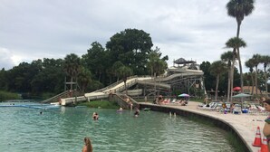 Ein Wasserpark mit Lazy River, Wasserrutschen und Poolbereich inklusive Liegestühle und Sonnenschirme.