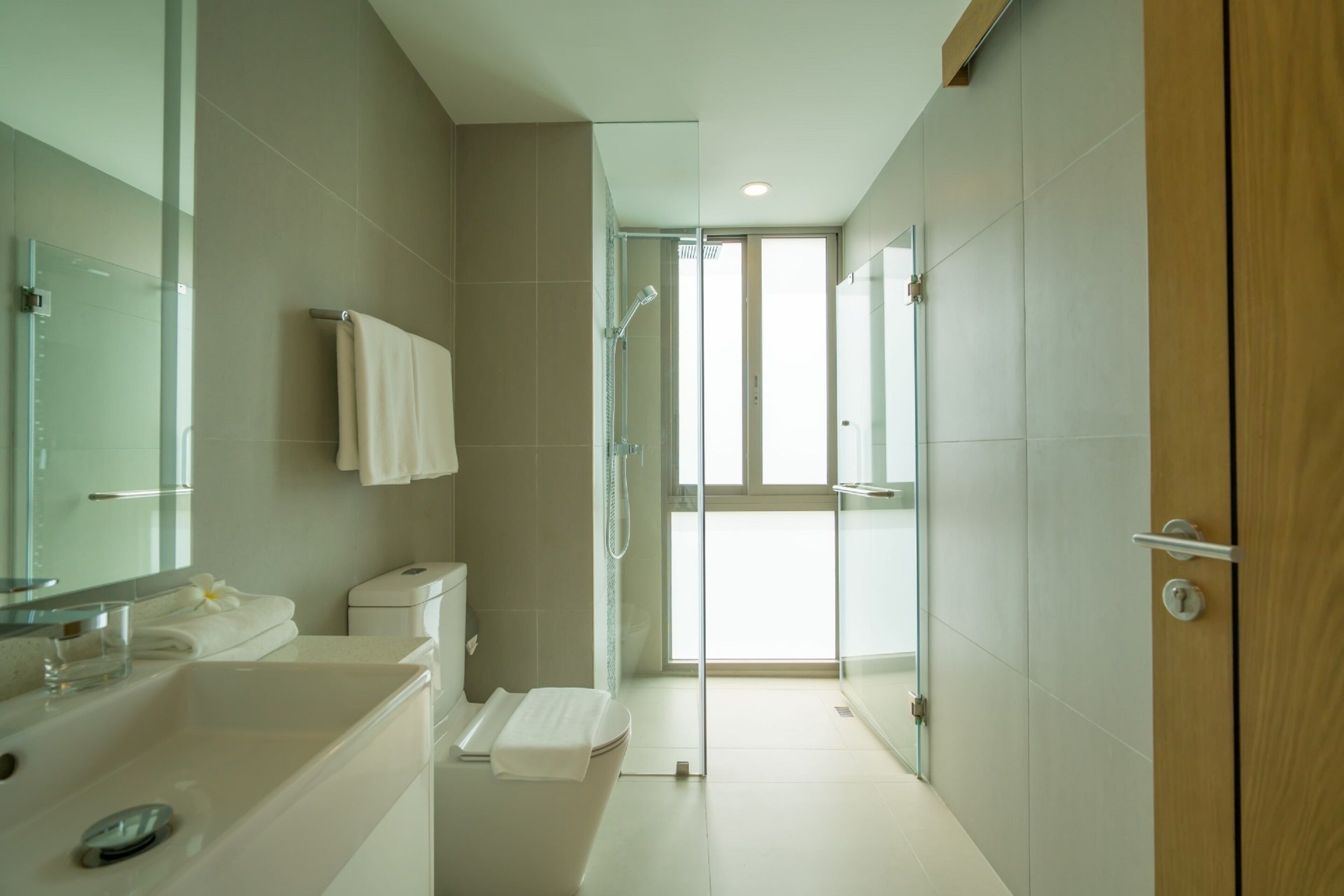 Een moderne badkamer met een glazen douche, toilet en wastafel.