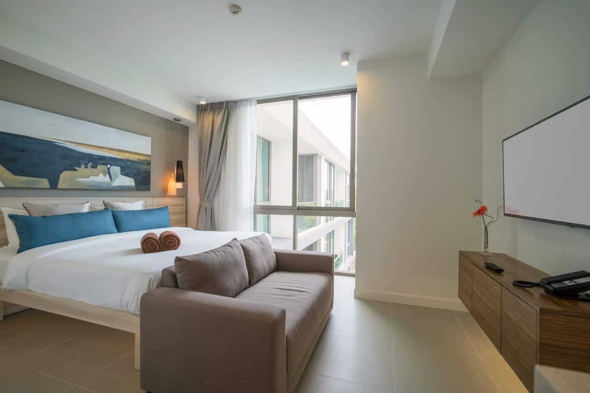 Une chambre d’hôtel moderne dotée d’un grand lit, d’un canapé, d’une télévision et d’un balcon avec vue.