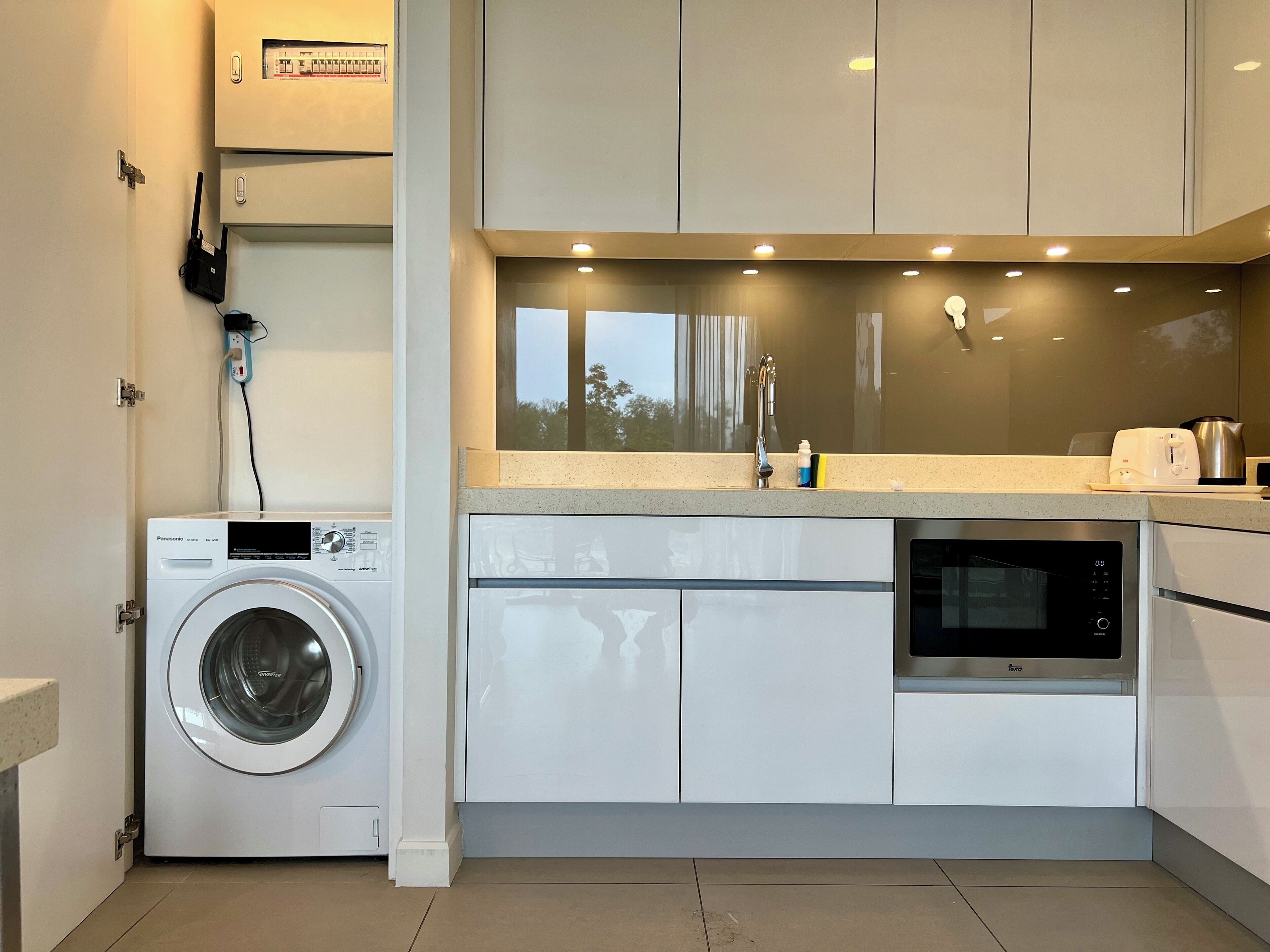 Una cocina moderna con lavadora integrada, microondas y un lavabo.