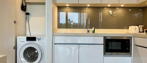 Una cocina moderna con lavadora integrada, microondas y un lavabo.