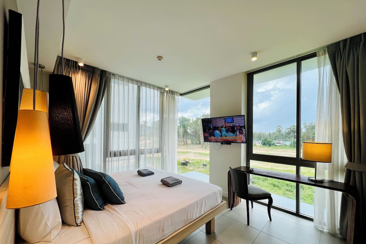 Une chambre d’hôtel moderne, dotée d’un grand lit, d’un bureau, d’une télévision et offrant une vue sur l’extérieur.