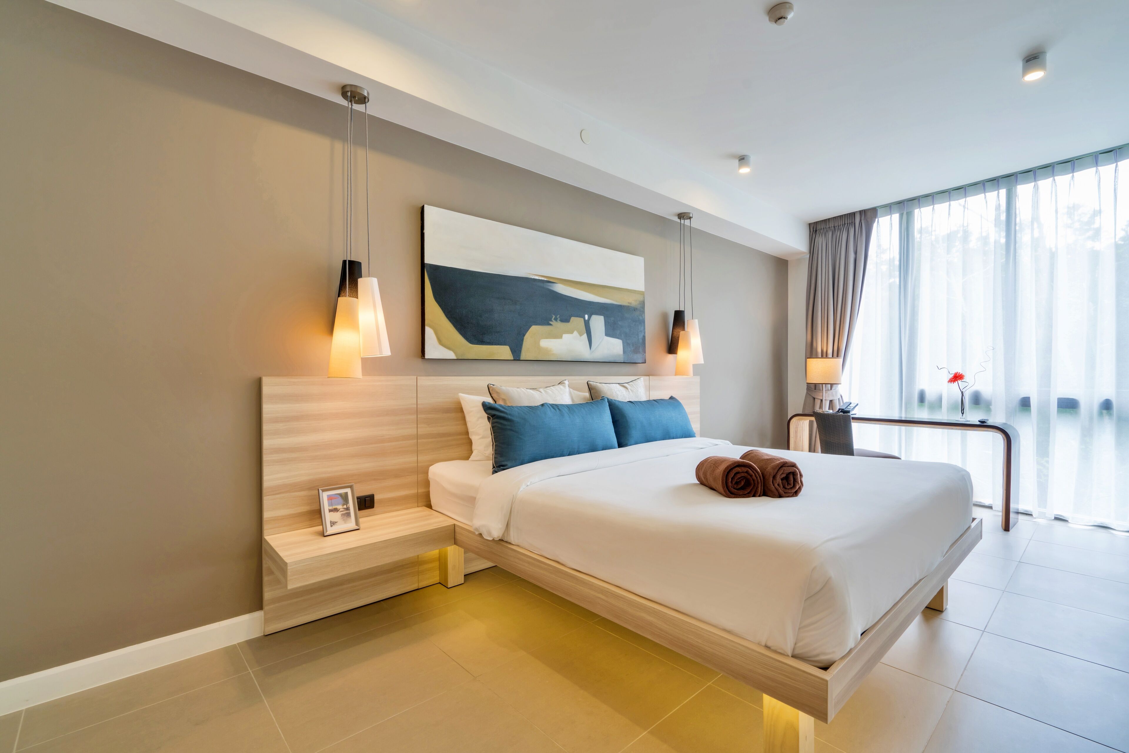 Una camera d'albergo moderna con un grande letto, comodini, un quadro e vista sull'esterno.