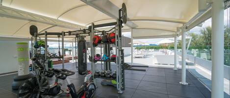 Un gimnasio con máquinas de cardio, equipo de levantamiento de pesas y vistas al exterior.