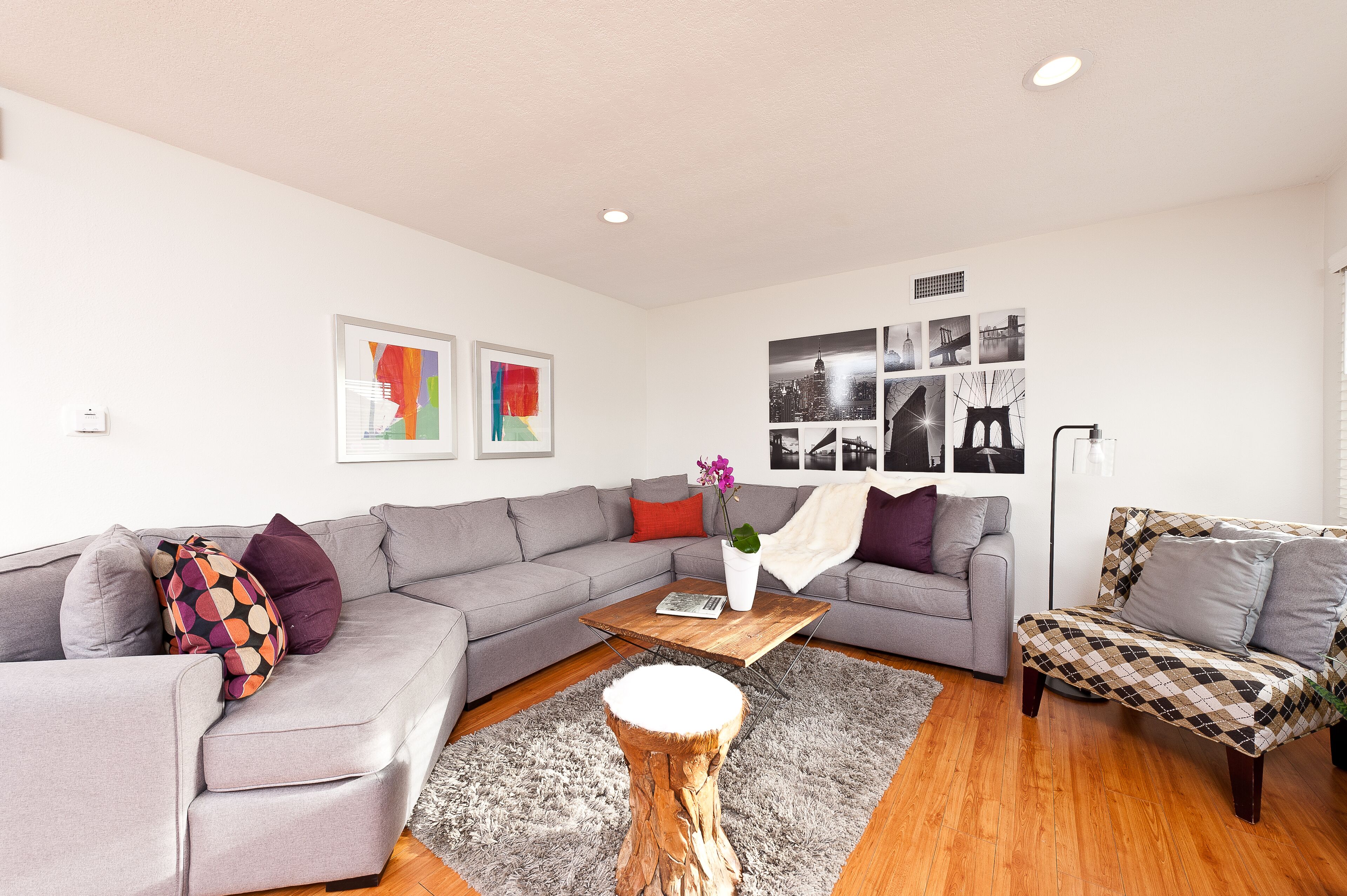 A modern living room with a grey sectional sofa, a wooden coffee table, and a patterned armchair.