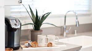 A kitchen counter with a coffee maker, two mugs with text, a plant, and a sink. - LAST MINUTE SPECIAL! WALK TO DISNEY & CONVENTION CENTER! Private heatedpool (Anaheim)