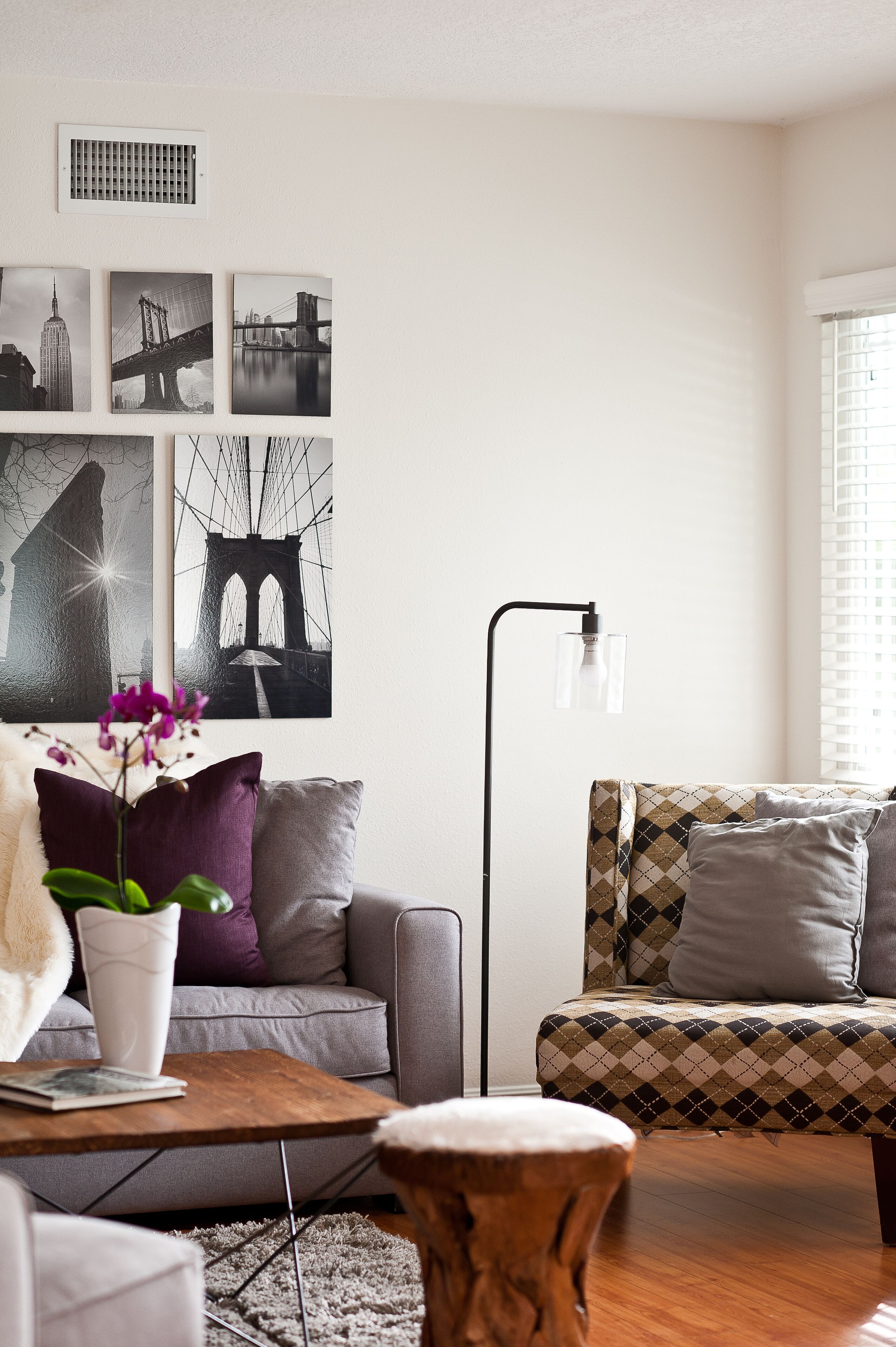 A modern living room with a grey sofa, a patterned sofa, a coffee table, and a floor lamp.