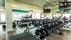 Une salle de sport équipée de matériel d’exercice, notamment des haltères et des tapis de course.