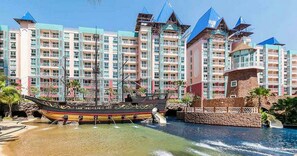 Un hôtel composé de plusieurs bâtiments, avec un espace aquatique agrémenté d’un bateau et une cascade.