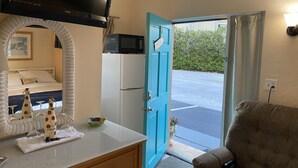 A room with a bed, a TV, a microwave, and a door leading outside. - PRIME STUDIO SAVE. UPSCALE BEACHFRONTS. SUN,SURF&SAND, TOWN 2 BLOCKS, PKG,CHAIRS (Madeira Beach)