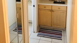 A narrow hallway with a small kitchen area, including wooden cabinets and a sink. - PRIME STUDIO SAVE. UPSCALE BEACHFRONTS. SUN,SURF&SAND, TOWN 2 BLOCKS, PKG,CHAIRS (Madeira Beach)