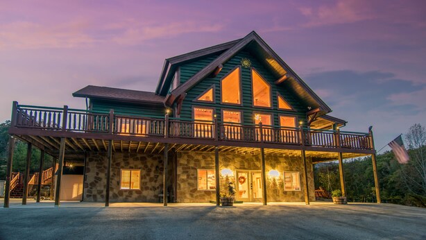 A two-story lodge with a stone facade, a balcony, and a flag. - Family Favorite! no curves, pets , theater, , yard , fire pit , min to strip  (SEVIERVILLE)