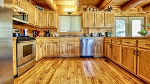 A wooden cabin-style kitchen with a stainless steel refrigerator, oven, and dishwasher. - Family Favorite! no curves, pets , theater, , yard , fire pit , min to strip  (SEVIERVILLE)