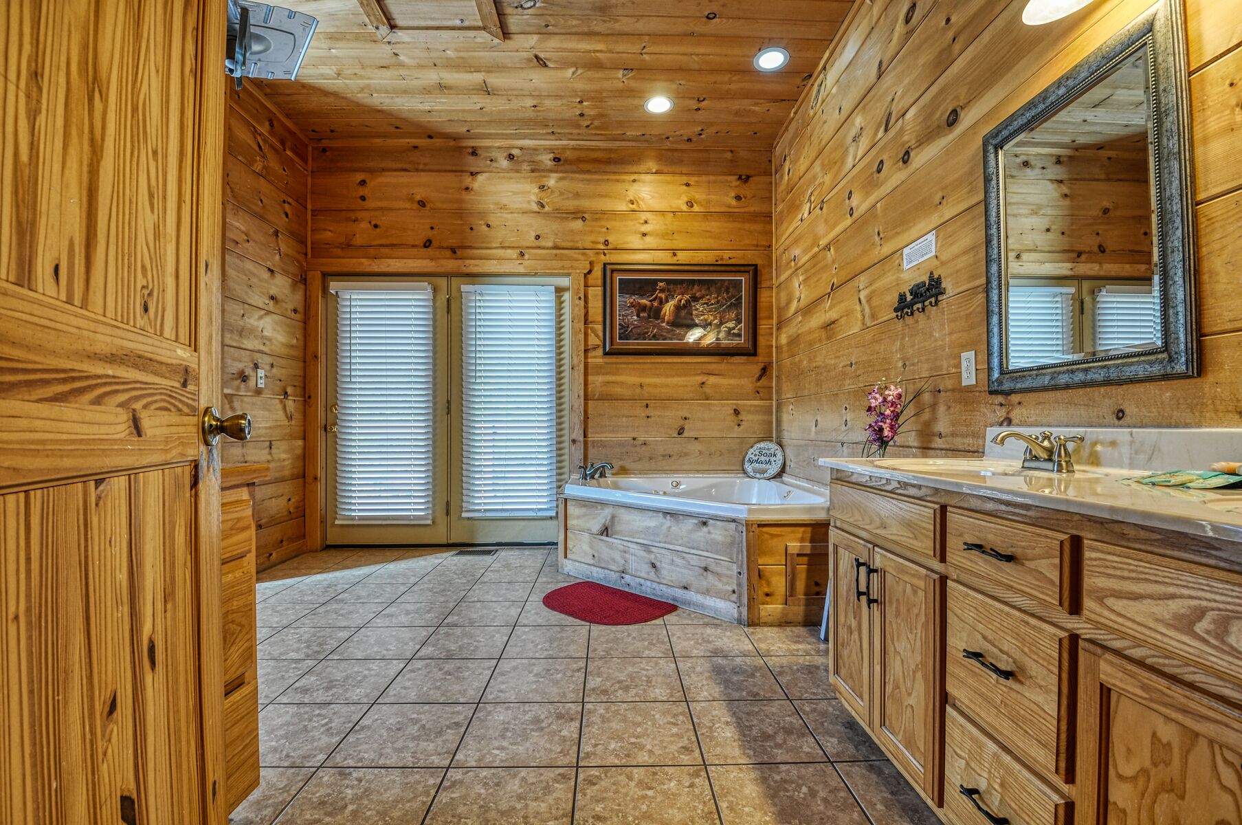A wooden cabin bathroom with a bathtub, sink, and large mirror.