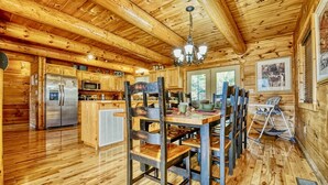 A rustic wooden cabin interior with a kitchen, dining area, and a child's high chair. - Family Favorite! no curves, pets , theater, , yard , fire pit , min to strip  (SEVIERVILLE)