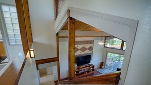 A wooden staircase with a view of a living room, a television, and a patterned rug. - Hale Waiaha Spacious Holualoa Home  (Holualoa)