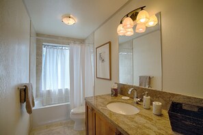 Une salle de bain avec un lavabo, un miroir et des toilettes.