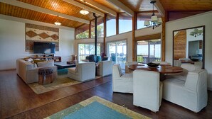 A spacious living room with wooden beams, a large TV, and comfortable seating. - Hale Waiaha Spacious Holualoa Home  (Holualoa)