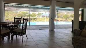 A spacious room with a view of a swimming pool, a dining table with chairs, and a sofa. - A little piece of heaven on the river (Port St Lucie)