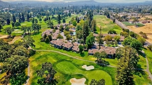 Vista aérea de uma área residencial com casas, gramados verdes e um campo de golfe.