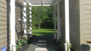 Un passage couvert menant à une maison dotée d’un jardin.