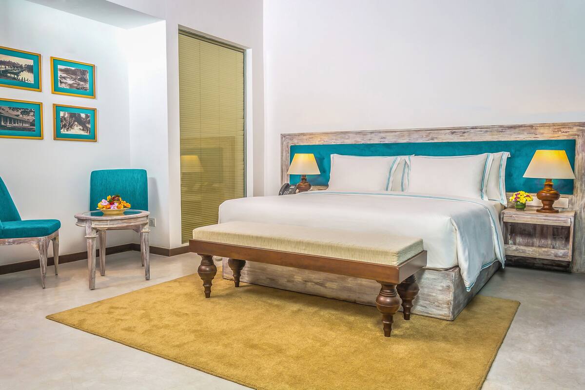 Una habitación de hotel con una cama, una silla, una mesita y un marco de fotos en la pared.