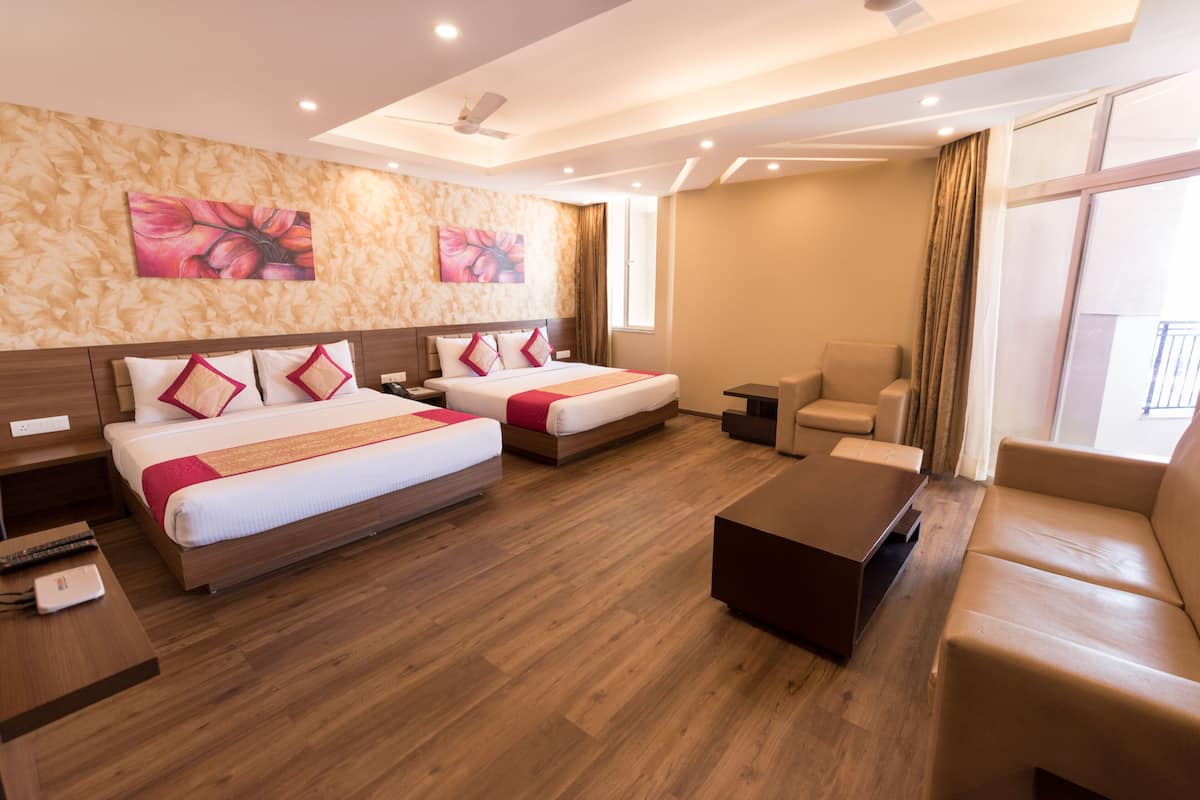 Une chambre d’hôtel avec deux lits, un canapé, une table basse et des œuvres d’art accrochées aux murs.