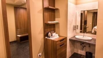 Un baño moderno con tocador de madera, lavamanos y espejo.