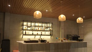 A bar area with a wooden ceiling, pendant lights, a bar counter, and a display of bottles. - Le ROI Digha (Kanthi)