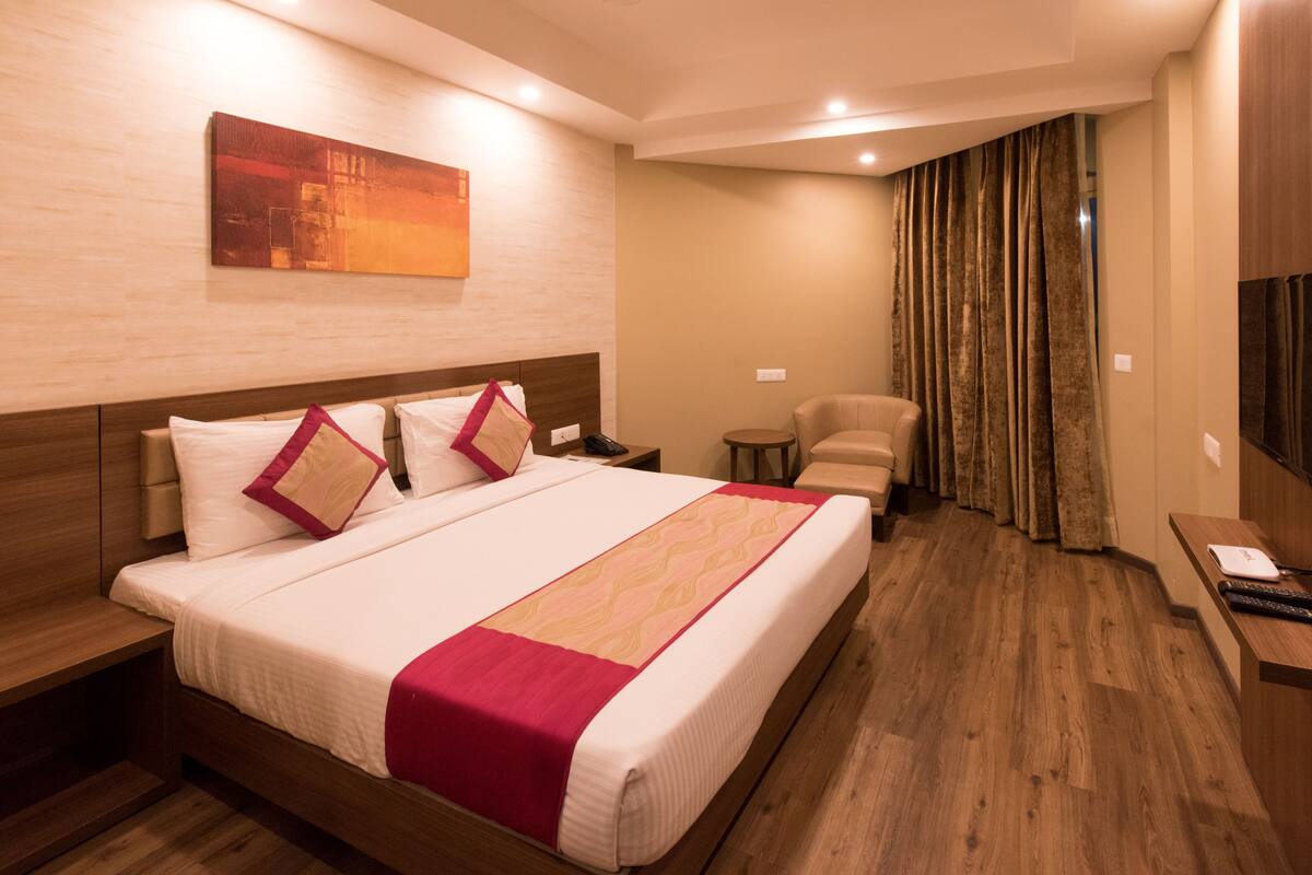 Une chambre d’hôtel avec un grand lit, un bureau, une chaise et un téléviseur.