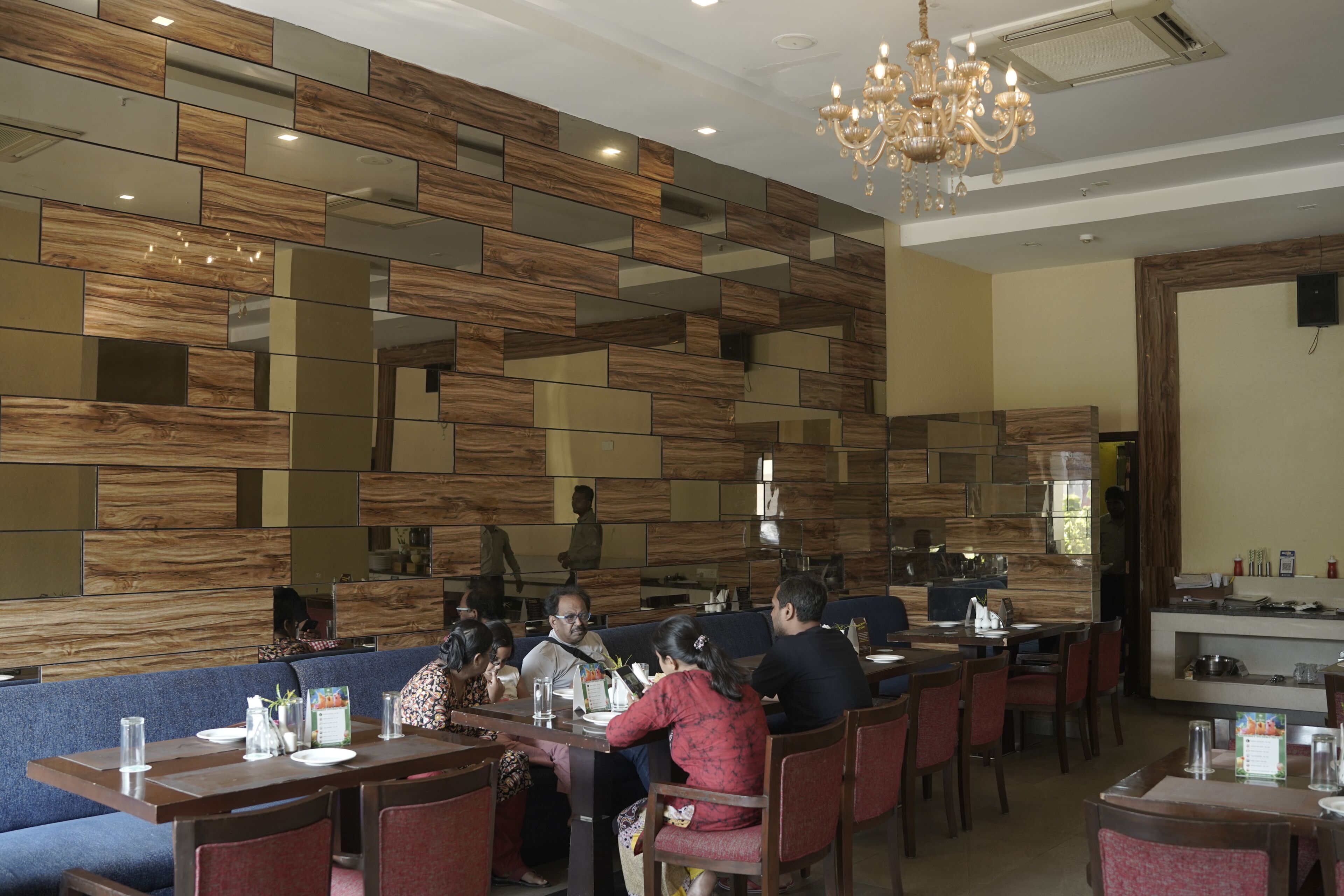 A restaurant with wooden wall panels, a chandelier, and seating arrangements.
