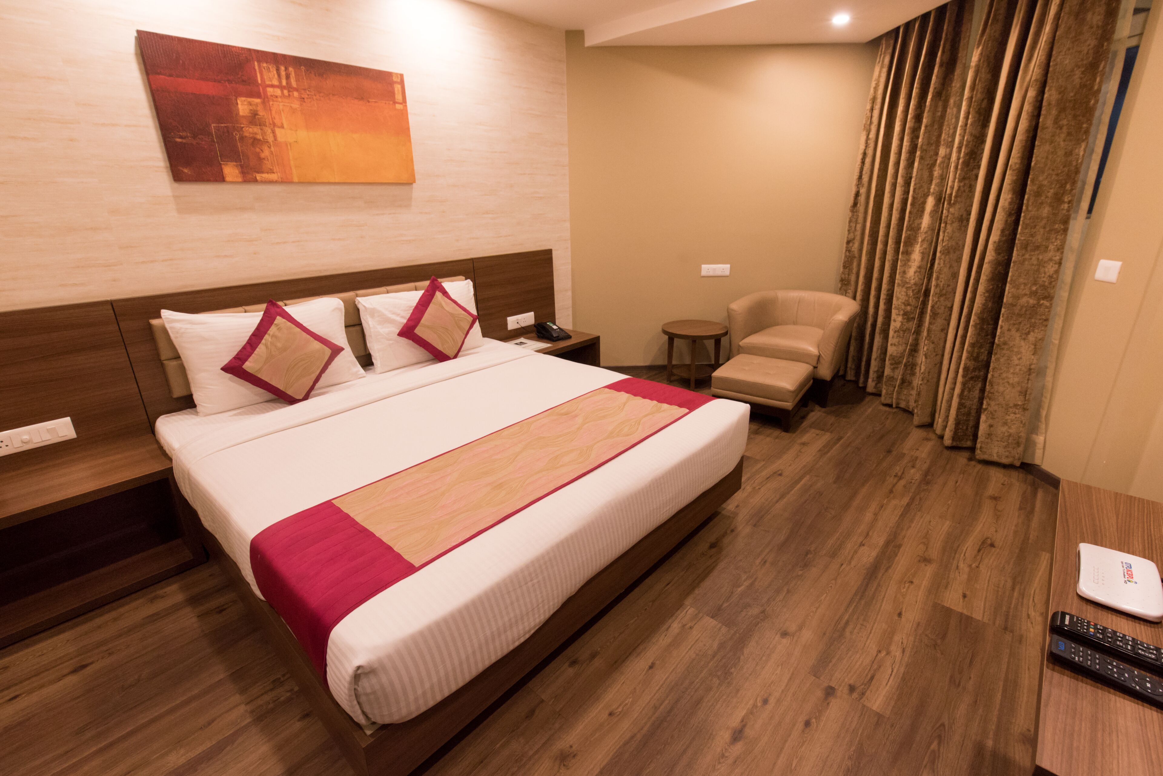 A hotel room with a large bed, a chair, a small table, and a TV.