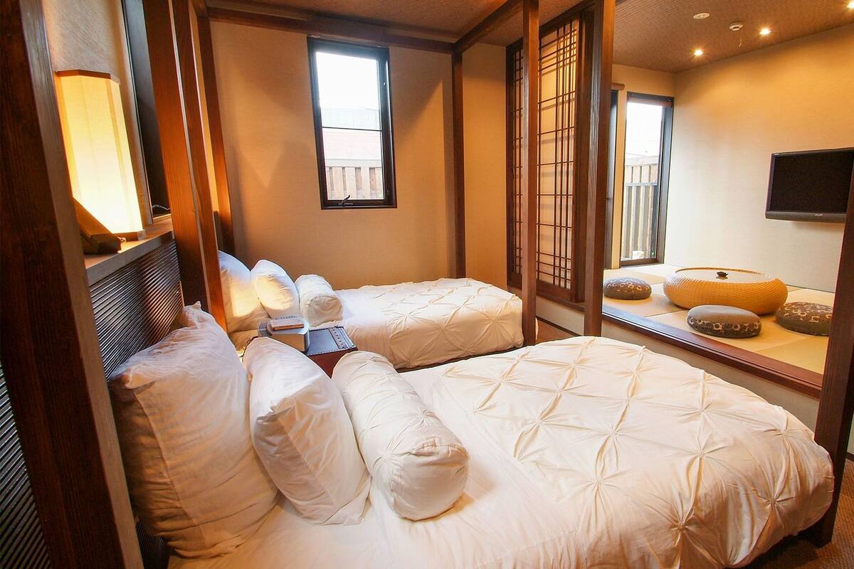 Une chambre d’hôtel avec deux lits, une table de chevet, une lampe, un téléviseur et une vue sur l’extérieur.