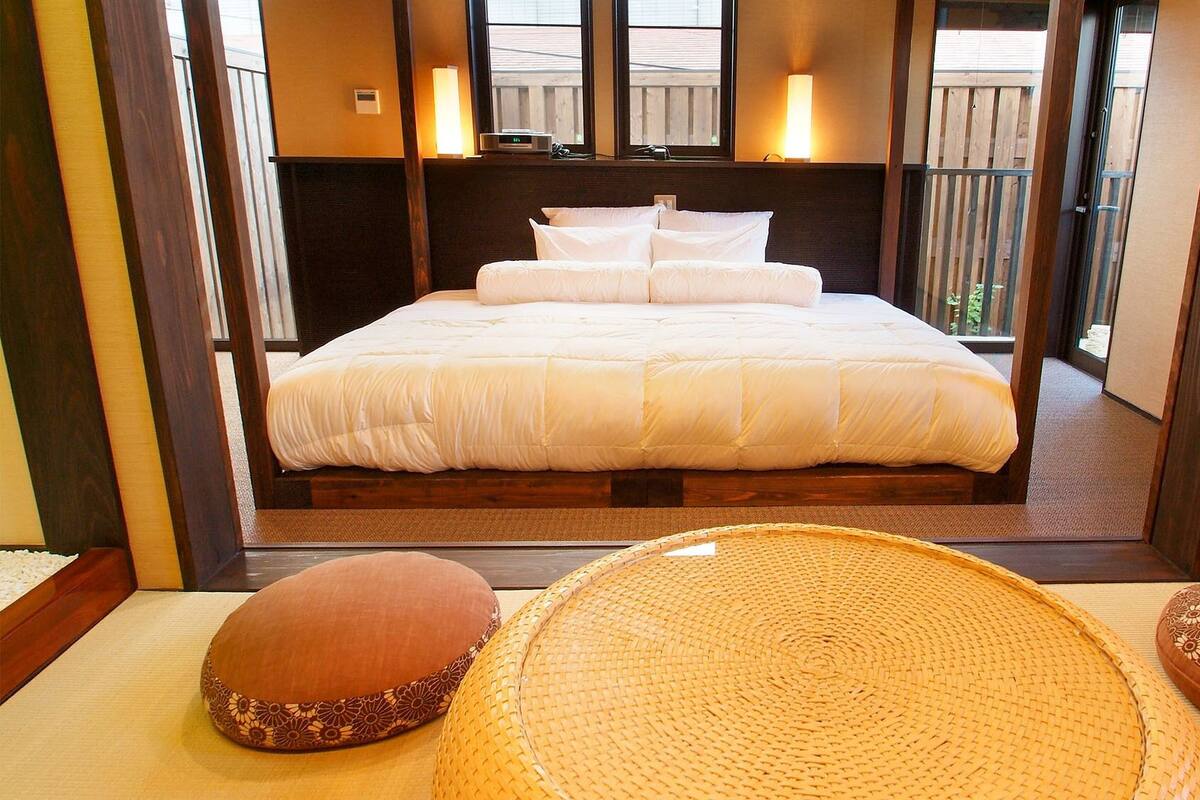 Une chambre d’hôtel avec un grand lit, une table de chevet, une lampe et une vue sur l’extérieur.