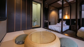 A traditional Japanese-style room with tatami flooring, a low wooden bed, and sliding doors. - Tsuruya (Aso)