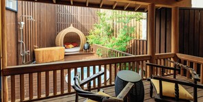 Une terrasse en bois avec un jacuzzi, un fauteuil suspendu et un banc en bois.