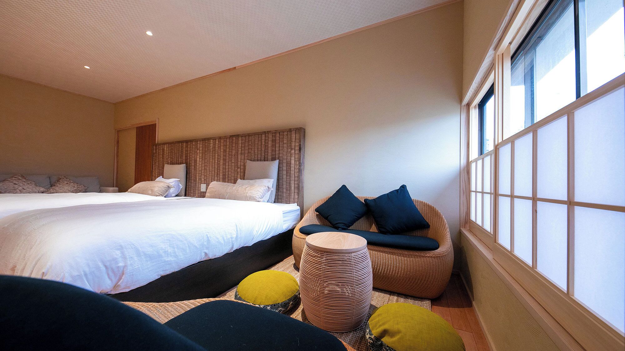 A hotel room with two beds, a sofa, a window, and a small table.