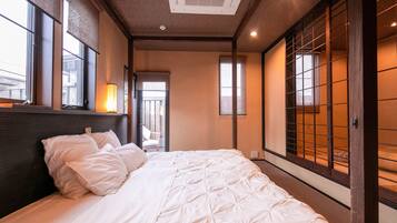 Quarto de hotel com cama grande, cabeceira de madeira e portas deslizantes com padrão de grade.