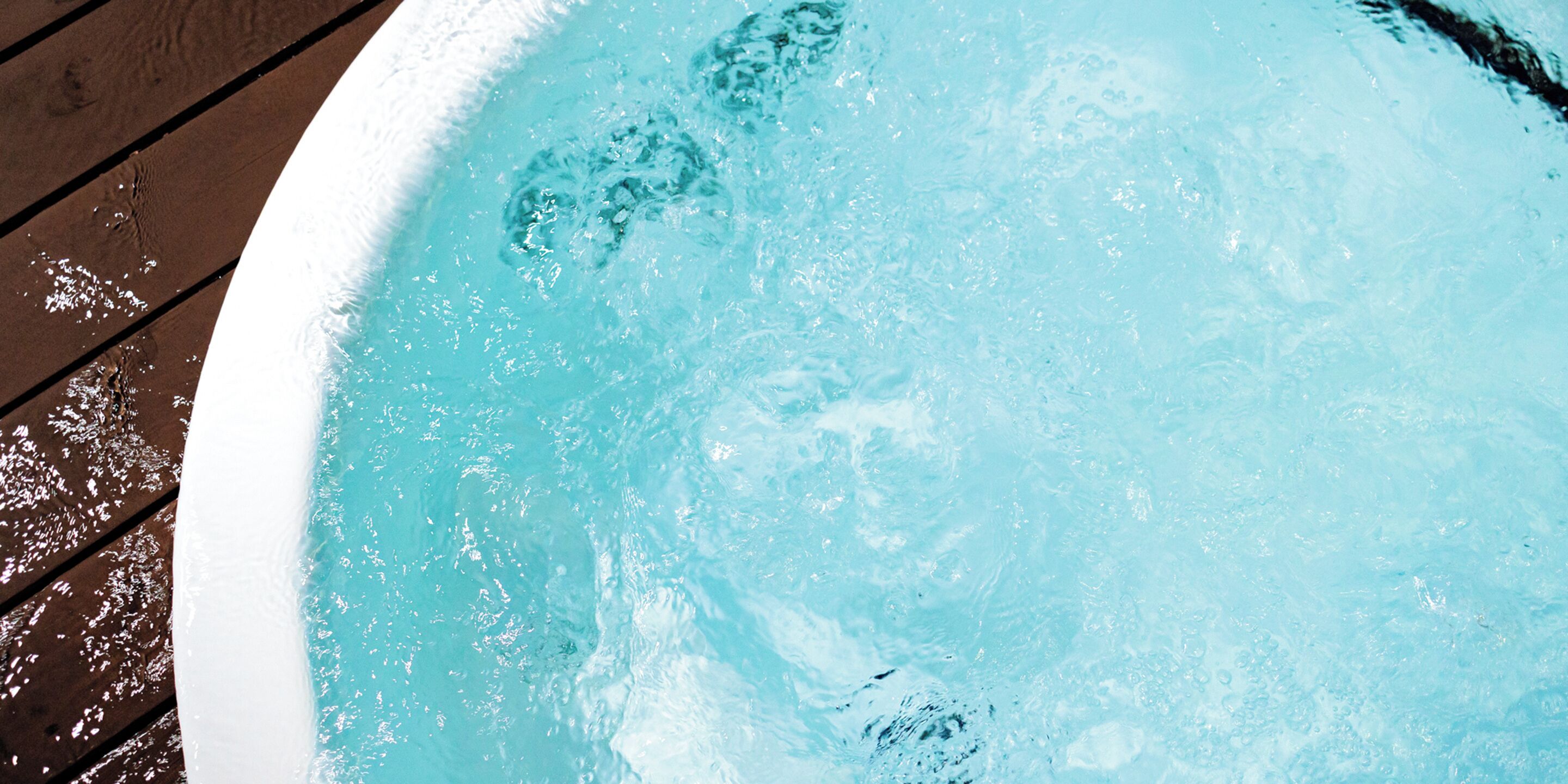 A hot tub with clear water, surrounded by a wooden deck.