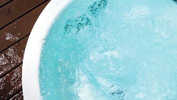 A hot tub with clear water, surrounded by a wooden deck.