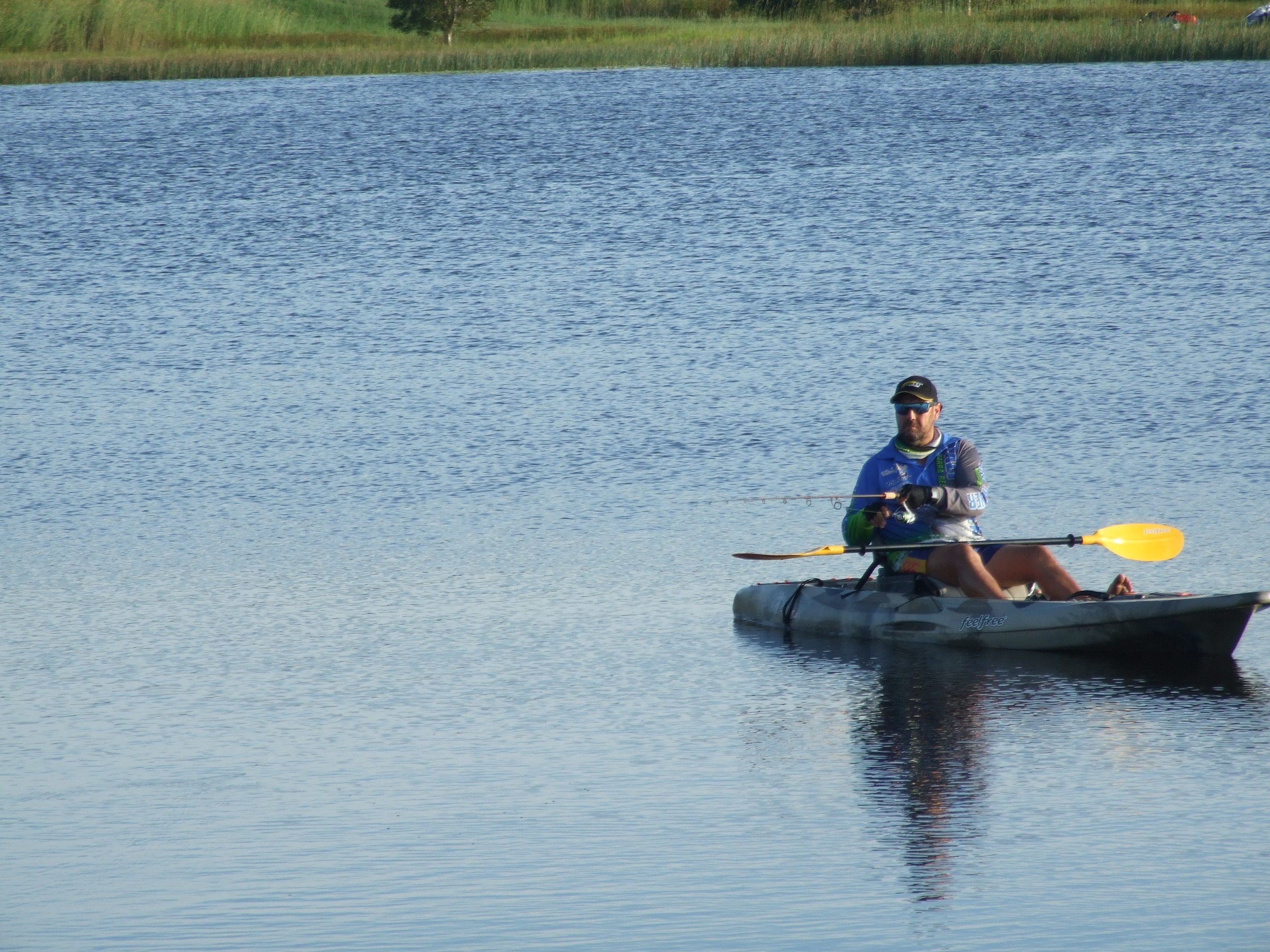 Une personne dans un kayak sur une étendue d'eau calme.
